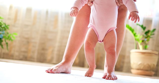 A child learns to walk with the help of an adult